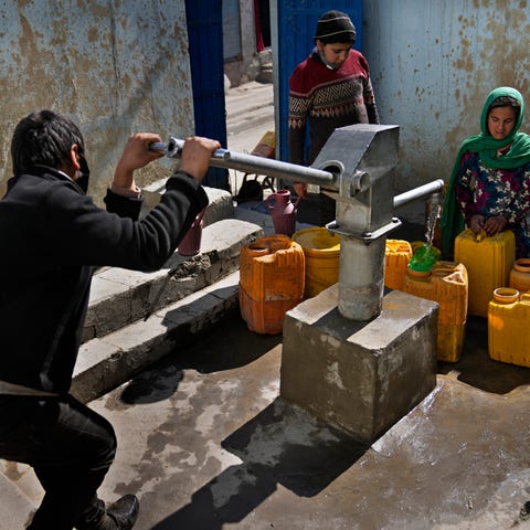 Afghans fill containers with water from a well at 