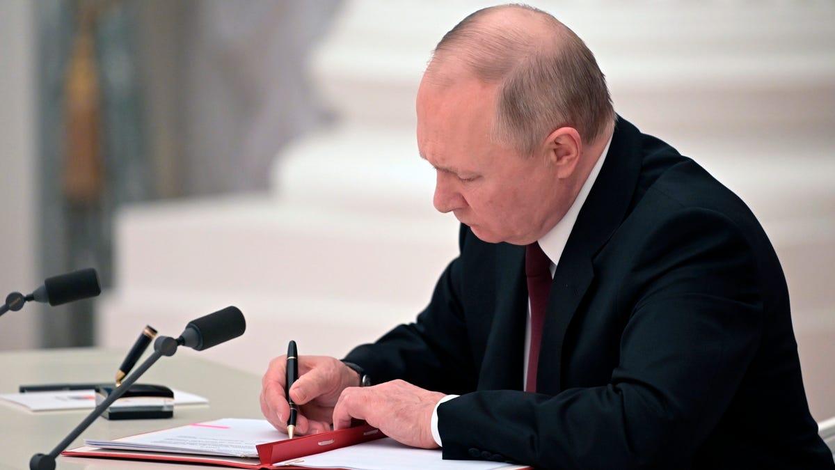 Russian President Vladimir Putin signs a document recognizing the independence of separatist regions in eastern Ukraine in the Kremlin in Moscow, Russia, Monday, Feb. 21, 2022. Russia's Putin has recognized the independence of separatist regions in eastern Ukraine, raising tensions with West. 