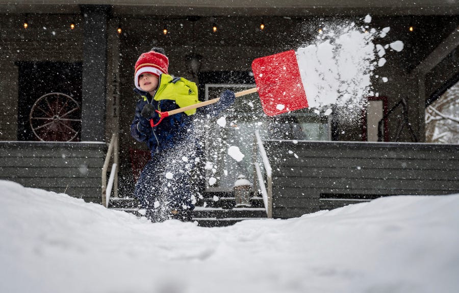 While his dad Jordan Apfelbaum shoveled the sidewalk, son Ari, 4, helps clear the front walkway of snow at their West 17th Avenue home, Monday, Feb. 21, 2022.