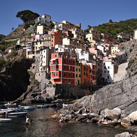 People rest on rocks near the village of Riomaggio