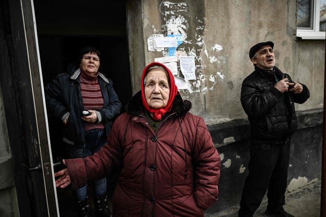 People stand at the door of their building's basement they use as a shelter during bombings in the town of Schastia, near the eastern Ukraine city of Lugansk, on Feb. 22, 2022, a day after Russia recognised east Ukraine's separatist republics and ordered the Russian army to send troops there as