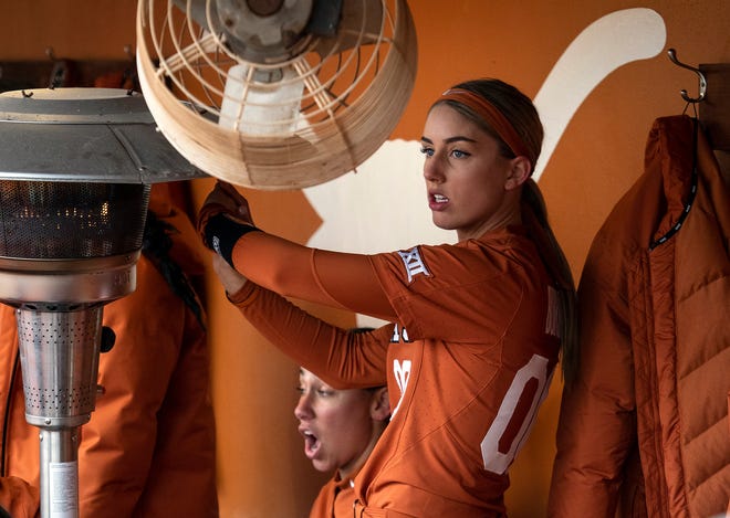 Texas outfielder Lauren Burke warms her hands in the dugout with a heater during a 2019 game against Boise State at McCombs Field in Austin. Expected bad weather in the Austin area this week has caused scheduling cancellations and postponements for the Texas Classic.