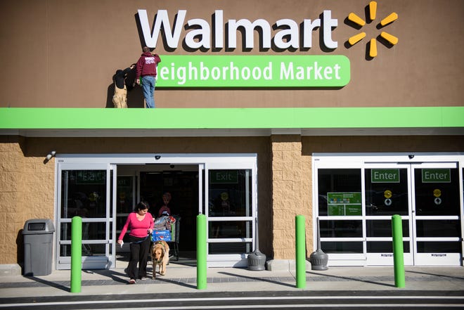 Workers work on the Walmart sign while shoppers come and go at the new Walmart Neighborhood Market on Raeford Road, Thursday, Jan. 8, 2015.