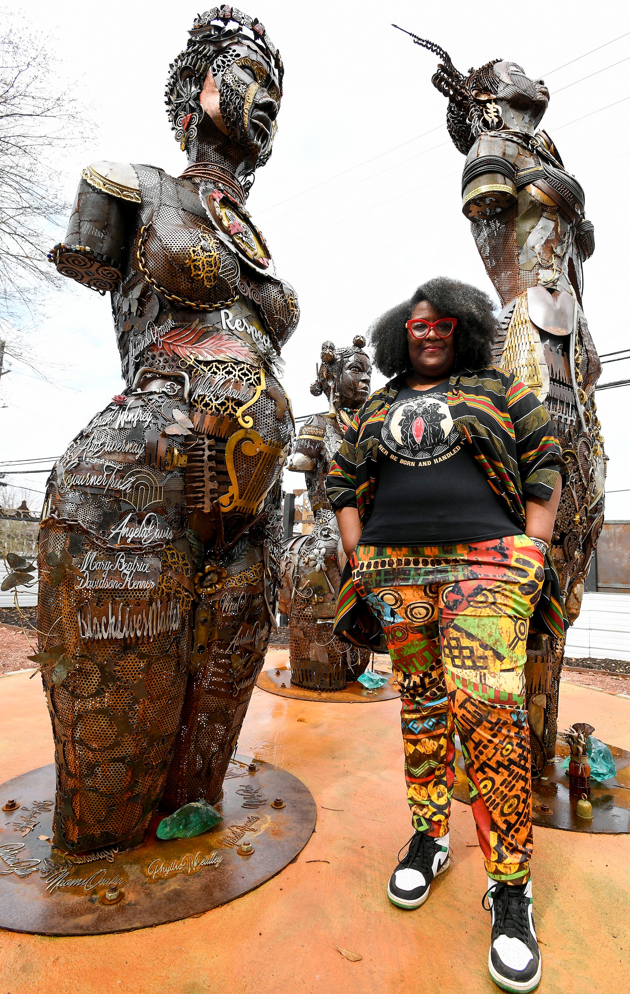 Michelle Browder poses beside the statues of Anarchy, Lucy and Betsey in the Mothers of Gynecology Park on the More Up Campus in Montgomery, Ala.