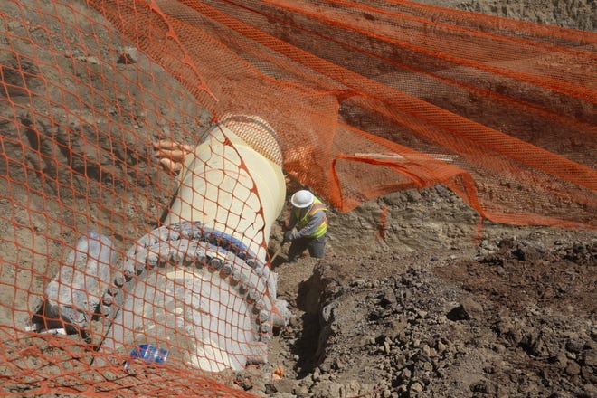 A construction worker shovels dirt from underneath a thrust block as part of the Navajo-Gallup Water Supply Project on April 15, 2021 in Sheep Springs.