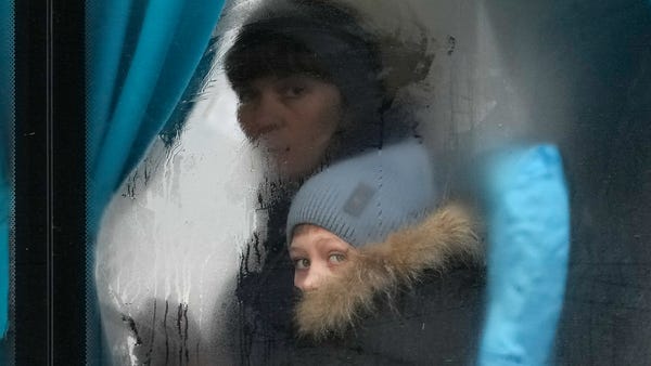 A woman and child peer out of the window of a bus 