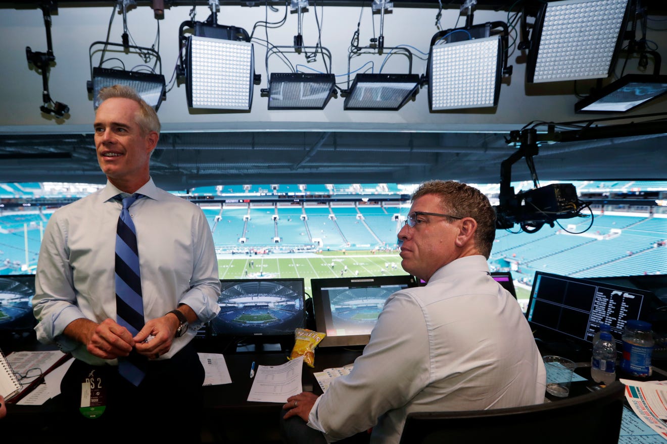 Fox Sports play-by-play announcer Joe Buck, left, and analyst Troy Aikman work in the broadcast booth.