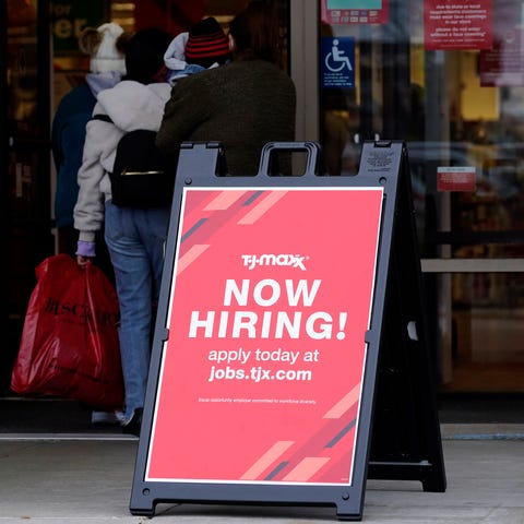 A hiring sign is displayed outside of a retail sto