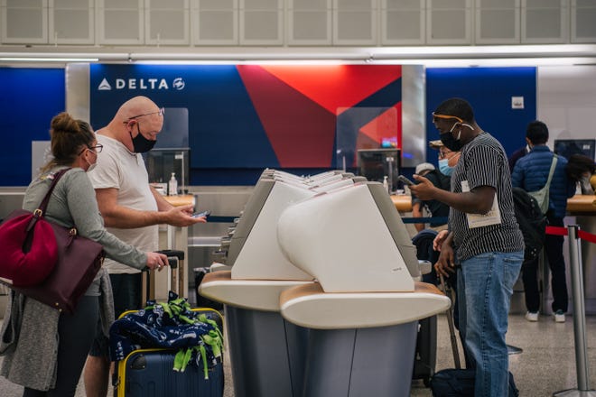 People check-in at a Delta station for departure flights at the George Bush Intercontinental Airport on Jan. 13, 2022, in Houston.
