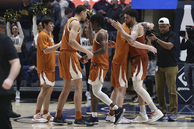 Texas players celebrate after a win against West Virginia during the second half of an NCAA college basketball game in Morgantown, W.Va., Saturday, Feb. 26, 2022.