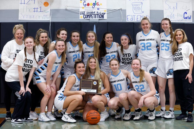 The Lansing Catholic girls team poses with their CAAC White championship trophy, Friday, Feb. 25, 2022, in Lansing.