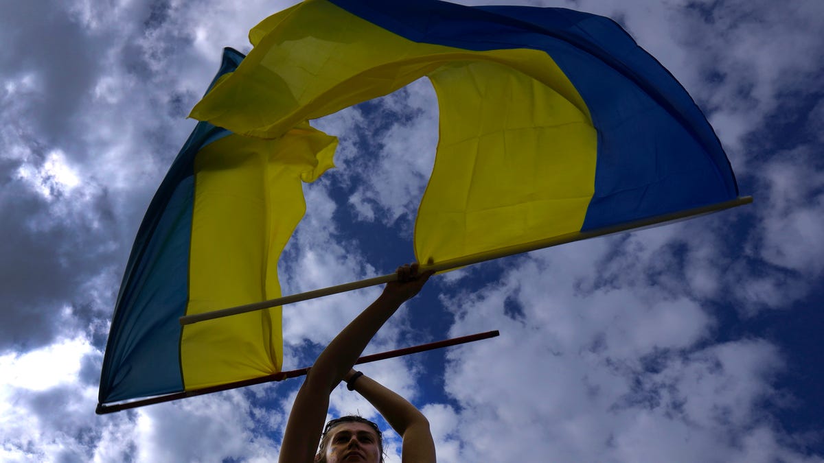 A Ukrainian protester, living in Cyprus, waves two Ukraine flags during a protest outside the Presidential palace in Nicosia, Cyprus, Saturday, Feb. 26, 2022. Russian troops stormed toward Ukraine's capital Saturday, and street fighting broke out as city officials urged residents to take shelter.