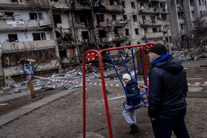 KYIV, UKRAINE - FEBRUARY 25: A boy plays on a swing in front of a damaged residential block hit by an early morning missile strike on February 25, 2022 in Kyiv, Ukraine. Yesterday, Russia began a large-scale attack on Ukraine, with Russian troops invading the country from the north, east and south, accompanied by air strikes and shelling. The Ukrainian president said that at least 137 Ukrainian soldiers were killed by the end of the first day.