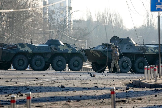 A soldier walks along Ukrainian armored vehicles blocking a street in Kyiv, Ukraine, Saturday, Feb. 26, 2022. Russian troops stormed toward Ukraine's capital Saturday, and street fighting broke out as city officials urged residents to take shelter.