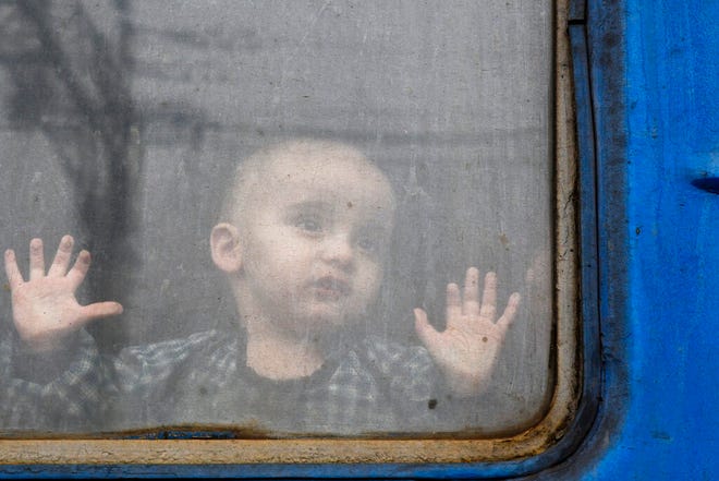 A child watches from from a train carriage waiting to leave Ukraine for western Ukraine at the railway station in Kramatorsk, eastern Ukraine, Sunday, Feb. 27, 2022. The U.N. refugee agency says nearly 120,000 people have so far fled Ukraine into neighboring countries in the wake of the Russian invasion. The number was going up fast as Ukrainians grabbed their belongings and rushed to escape from a deadly Russian onslaught. (AP Photo/Andriy Andriyenko)