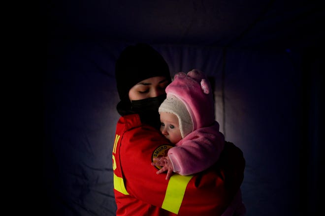 An employee from the Emergency Situation Inspectorate soothes the crying baby of a family fleeing the conflict from neighbouring Ukraine at the Romanian-Ukrainian border, in Siret, Romania, Saturday, Feb. 26, 2022.