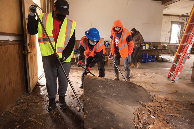 Students in the construction arts program at Fort Hayes High School remove old plywood flooring from the Fort Hayes gatehouse.