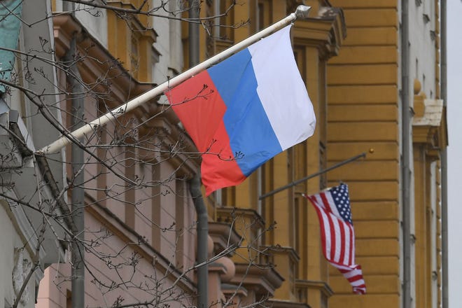 A Russian flag flies next to the US Embassy in Moscow last April.  Cybersecurity professionals are urging Americans to protect themselves from possible Russian cyberattacks.