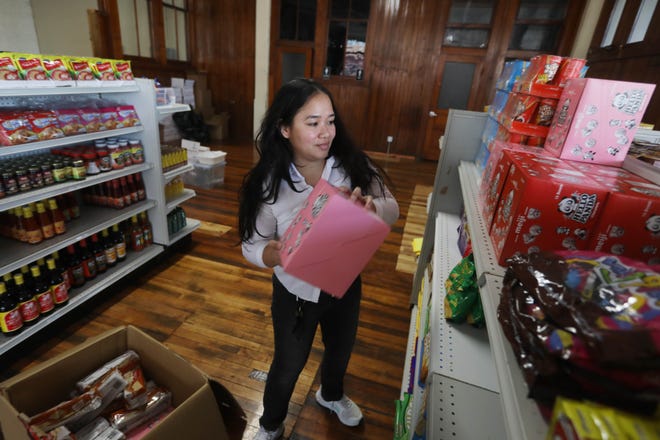 Leonilyn Richardson stocks the shelves of her soon-to-open Filipino and Asian grocery store, Lynne's Food Cravings, on Wednesday in the first-floor commercial retail space of Blaul Lofts in downtown Burlington.
