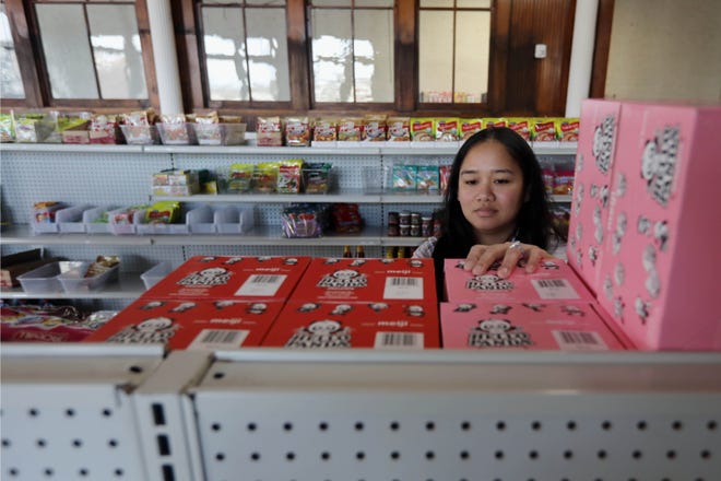 Leonilyn Richardson stocks the shelves of her soon-to-open Filipino and Asian grocery store, Lynne's Food Cravings, on Wednesday in the first-floor commercial retail space of Blaul Lofts in downtown Burlington.