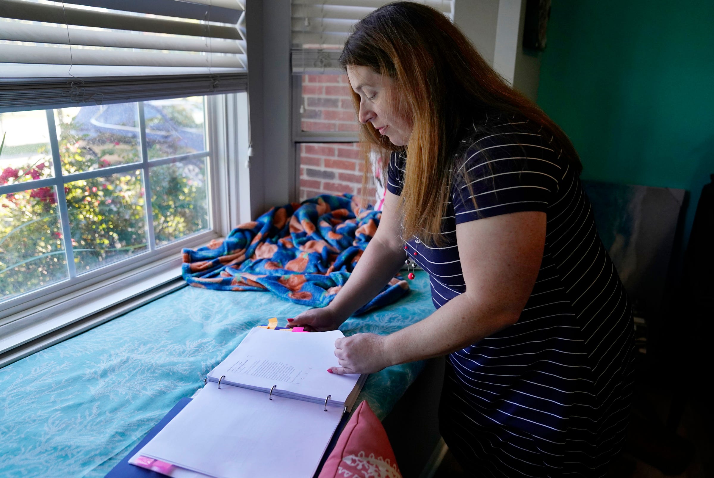 Kara Stamiris, 42, of Ypsilanti photographed Oct. 18 at her home. She keeps a binder tracking her efforts to find schooling for her nieces and nephew.