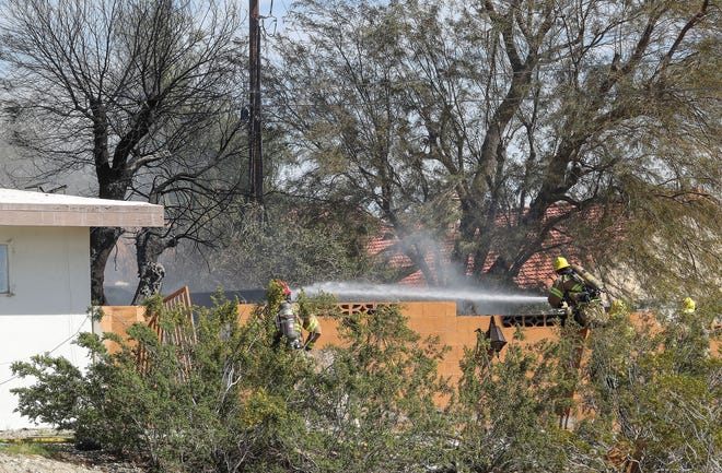 Firefighters extinguish the smoldering backyard at the home at 68241 Calle Blanco in Desert Hot Springs, Calif., March 2, 2022.  A fire broke out outside of the home and damaged some of the structure.