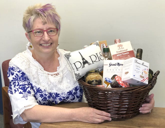 Global Ties Akron Executive Director Michelle Wilson with an international themed gift basket to be auctioned off at their upcoming Passport to Wine & Dine event.