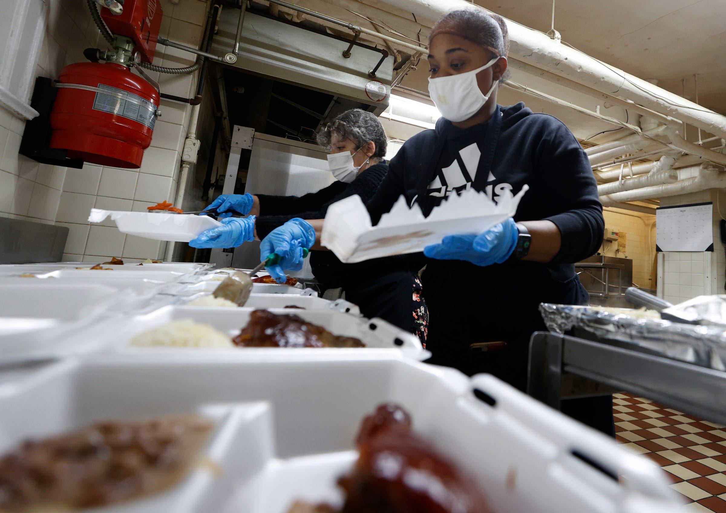 Temika Wallace, 36 of Detroit and the head chef, adds beans into to-go boxes for seniors as part of the meal program at the St. Patrick Senior Center in Detroit on Wednesday, March. 2, 2022.