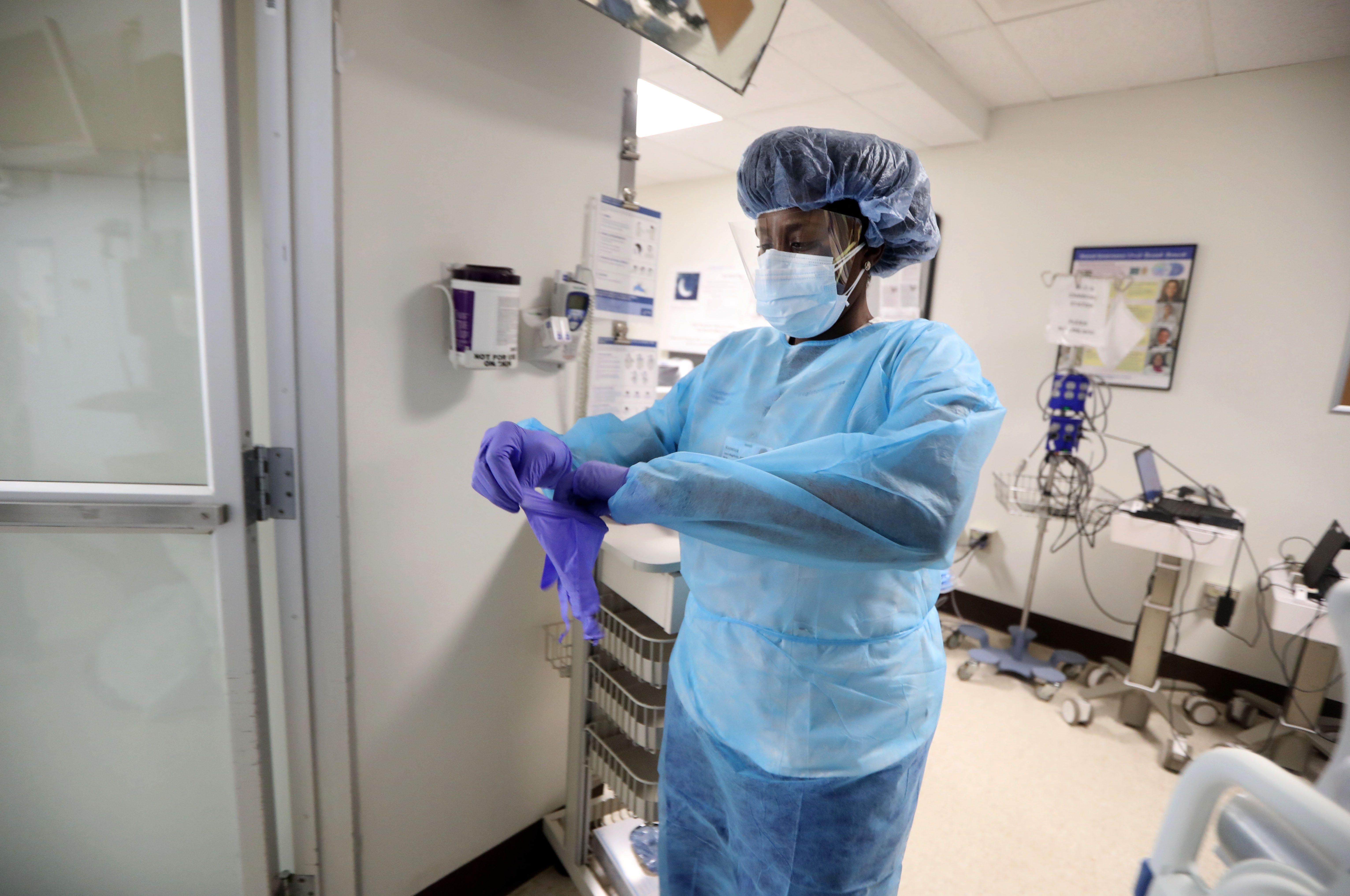 Vanessa Jean-Baptiste, a registered nurse in the intensive care unit at Northern Westchester Hospital in Mount Kisco, dons PPE equipment before entering the room of a patient with COVID-19 March 1, 2022. Two years into the COVID19 pandemic, Jean-Baptiste continues to work three 7:00 pm to 7:00 am shifts a week in the hospital's ICU.