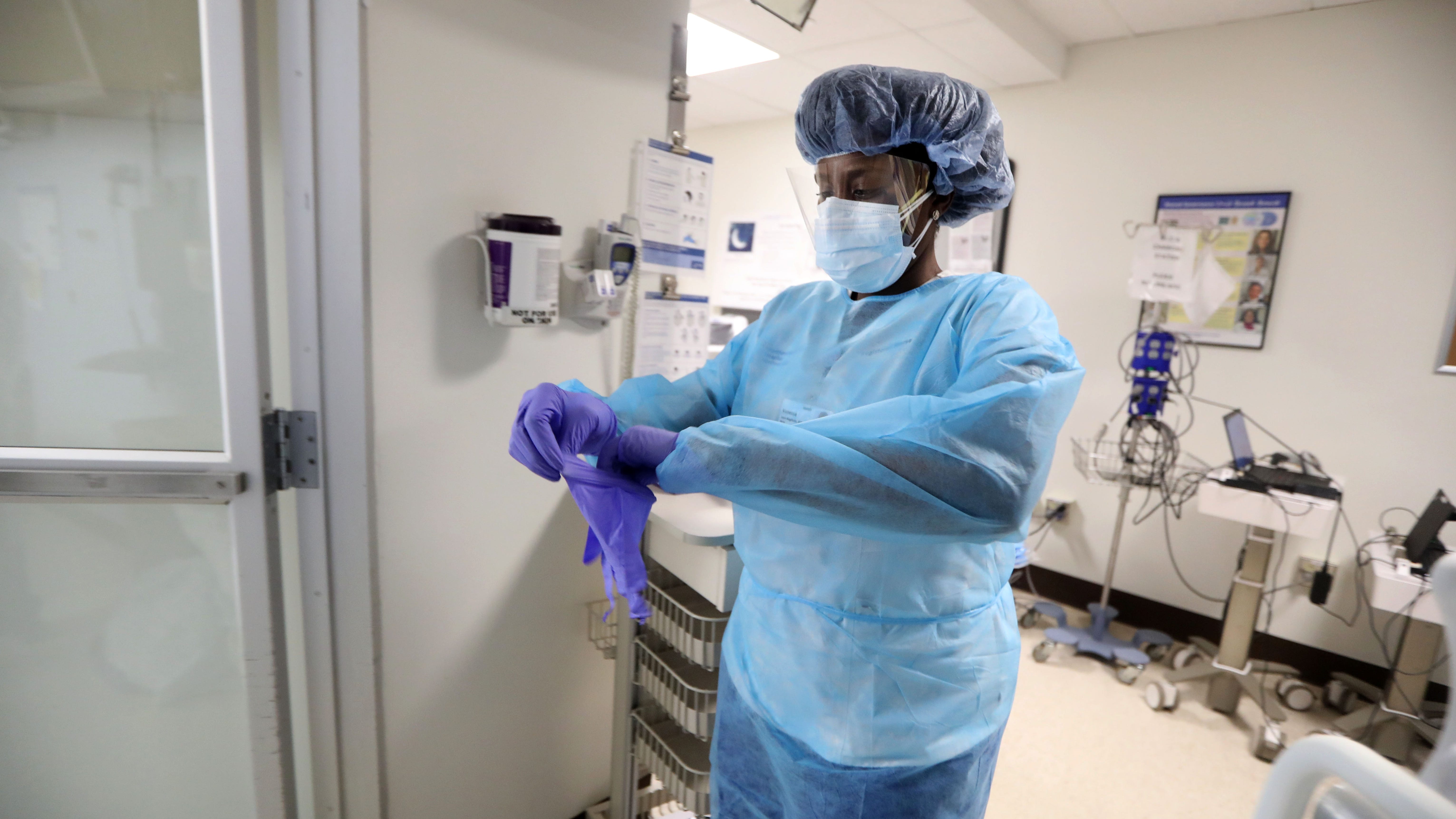 Vanessa Jean-Baptiste, a registered nurse in the intensive care unit at Northern Westchester Hospital in Mount Kisco, New York, dons PPE equipment before entering the room of a patient with COVID-19 on March 1, 2022.