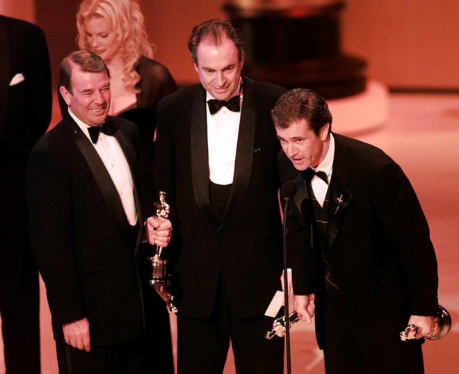 Mel Gibson, right, accepts the award for Best Picture for "Braveheart" at the 68th Annual Academy Awards in Los Angeles, Monday, March 25, 1996. Looking on are co-producers Alan Ladd Jr., left, and Bruce Davey.