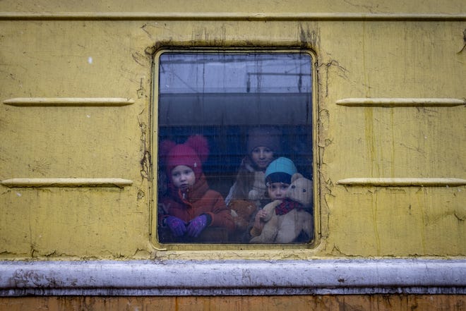 Children look out from a window of an unheated car of an emergency evacuation train traveling from Kharkov to Lviv on March 3, 2022.