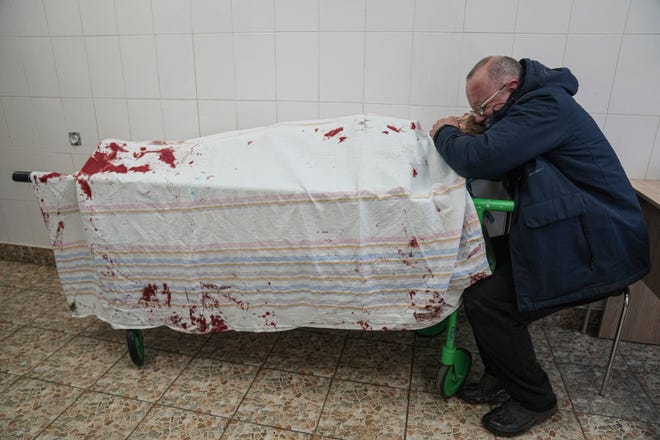 A father cries on his son's lifeless body lying on a stretcher at a maternity hospital converted into a medical ward in Mariupol, Ukraine, on March 2, 2022.