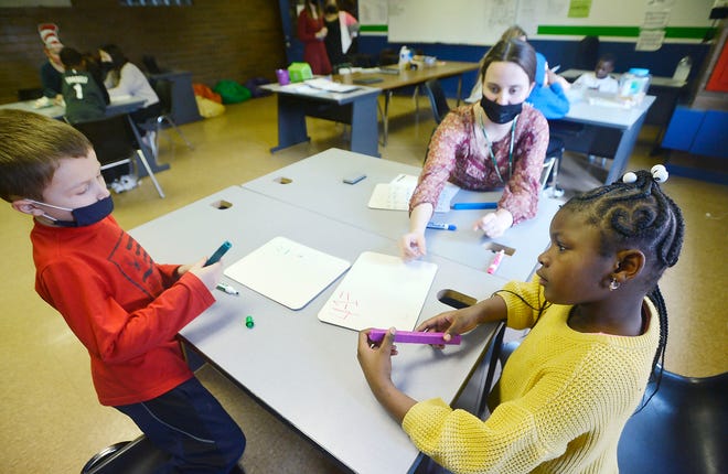 Six-year-olds Nick Wisniewski, left, and Londyn Williams, right, work on math problems with Sydnee Hitchcock, 22, at the Booker T. Washington Center on March 2. The Erie School District is using pandemic-relief funding to pay for after-school programs at the city's community centers, and the district is considering raising taxes to retain the programs when the federal pandemic money runs out in September 2024.