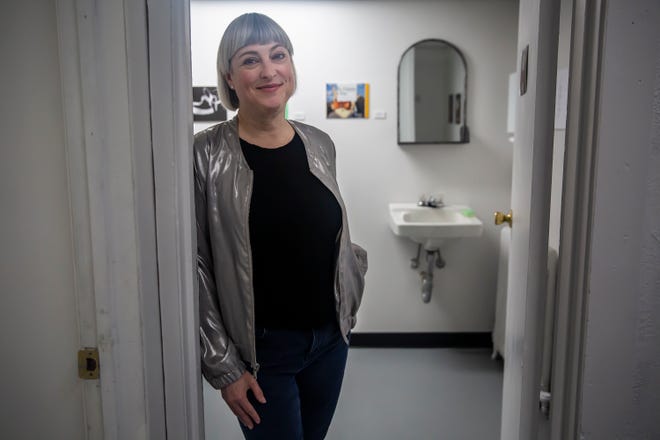 Des Moines artist Larassa Kabel poses for a photo outside of the bathroom art exhibit inside the Fitch Studios building on Feb. 28. The show is called "Lost and Found," featuring found art and poetry.