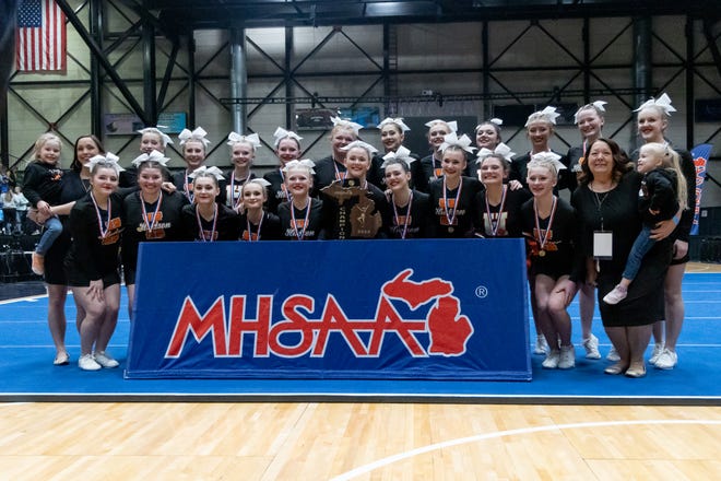 The Hudson competitive cheer poses with the Division 2 state championship trophy Friday at the Delta Plex in Grand Rapids.