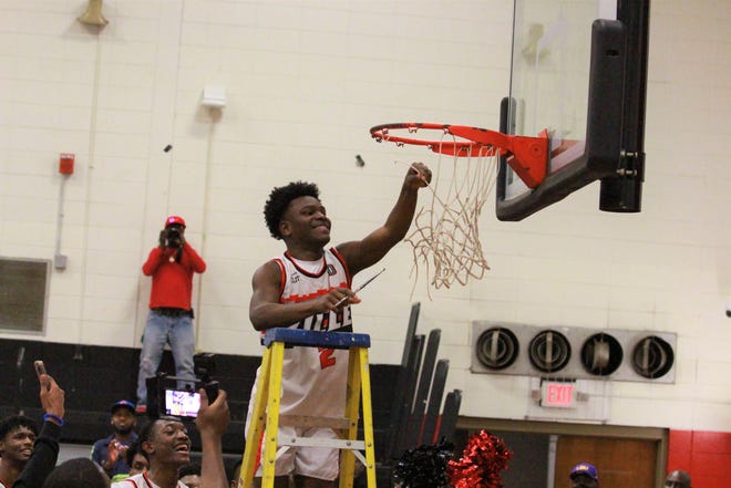 Tiger senior point guard Lawrence Forcell helps cut down the net following Donaldsonville’s quarterfinal win over Iowa.