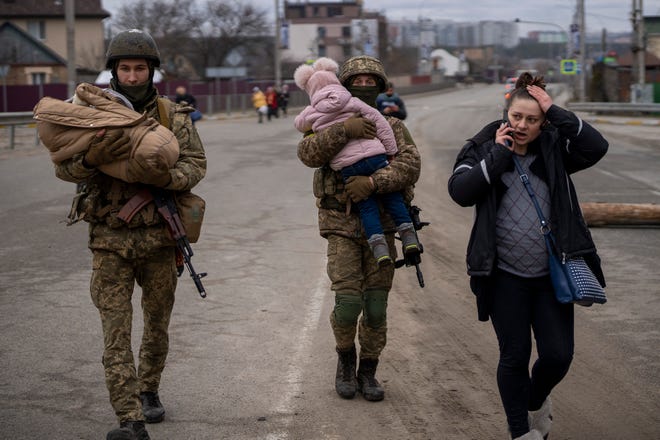 Tentara Ukraina menggendong bayi dan membantu keluarga yang melarikan diri untuk menemukan kendaraan setelah menyeberangi sungai Irpin di pinggiran Kyiv, Ukraina, Sabtu, 5 Maret 2022.