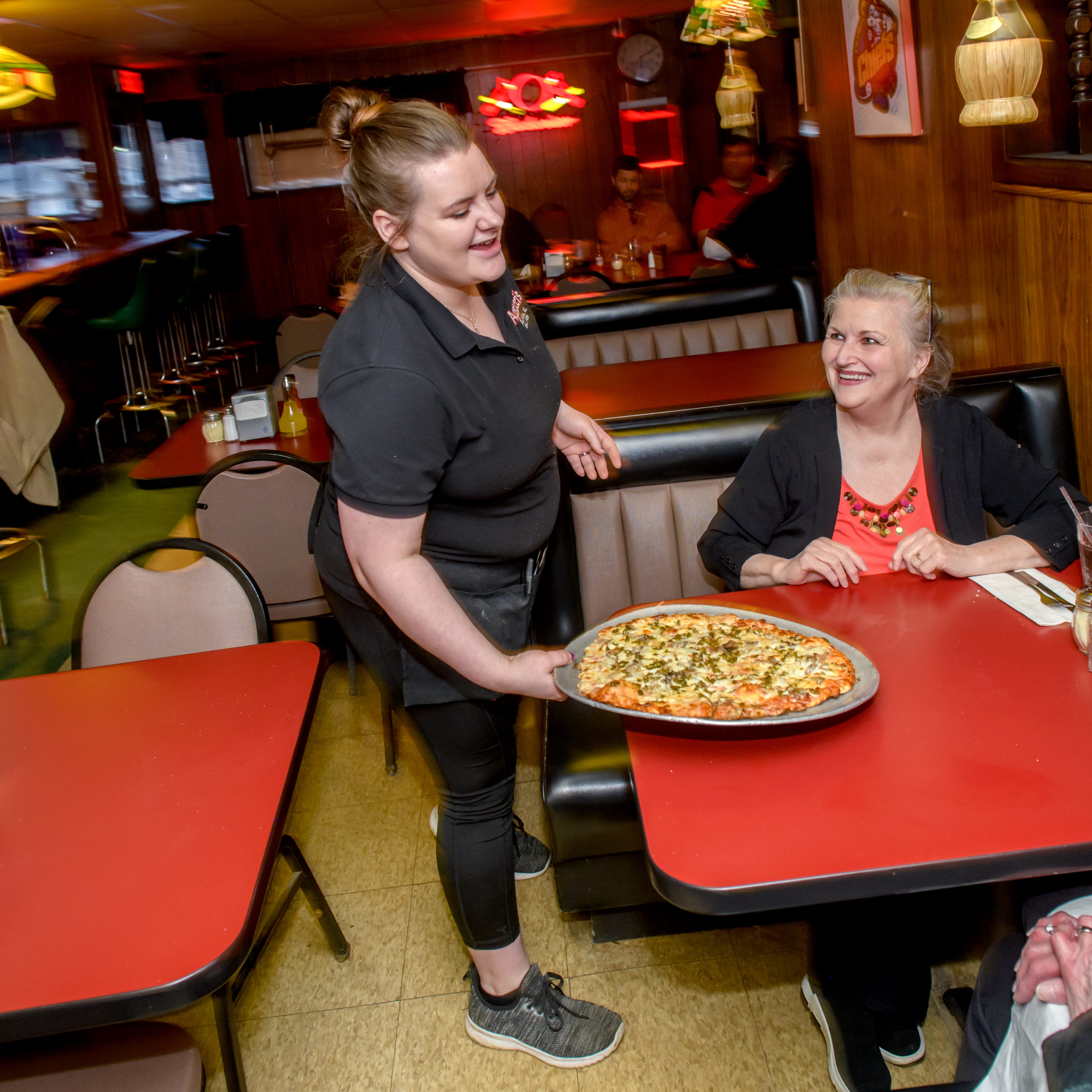 Agatucci's server Breeannah Burley delivers a pizza to customers at the popular longstanding Peoria restaurant at 2607 N. University Street.