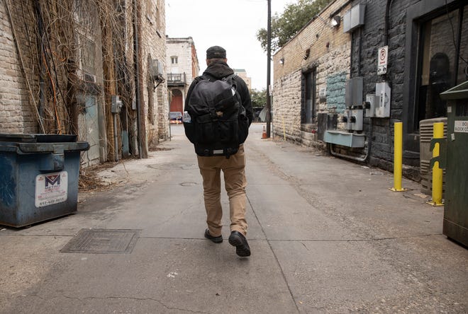 Thom Woodward walks in an alley in downtown Austin. Woodward’s electric guitar and other valuables were taken from a locked bin at the city-run Violet KeepSafe Storage facility, leaving him with just what he has in his backpack.