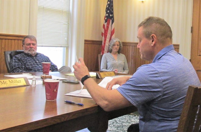 Holmes County Engineer Chris Young looks over a bid for the Bunny John Bridge repair project as Holmes County Commissioner Rob Ault and human resources coordinator Misty Burns look on Monday at the commissioners meeting.