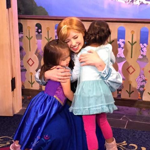 Anna embraces two young guests at Walt Disney Worl