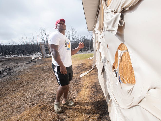 Ordavion McChristian points out the melted siding and other damage to his house on Whitehead Boulevard in Panama City as wildfires continue to burn through the area Tuesday. While McChristian's house was spared with minor damage, the two houses directly next to his house were totally consumed by fire.