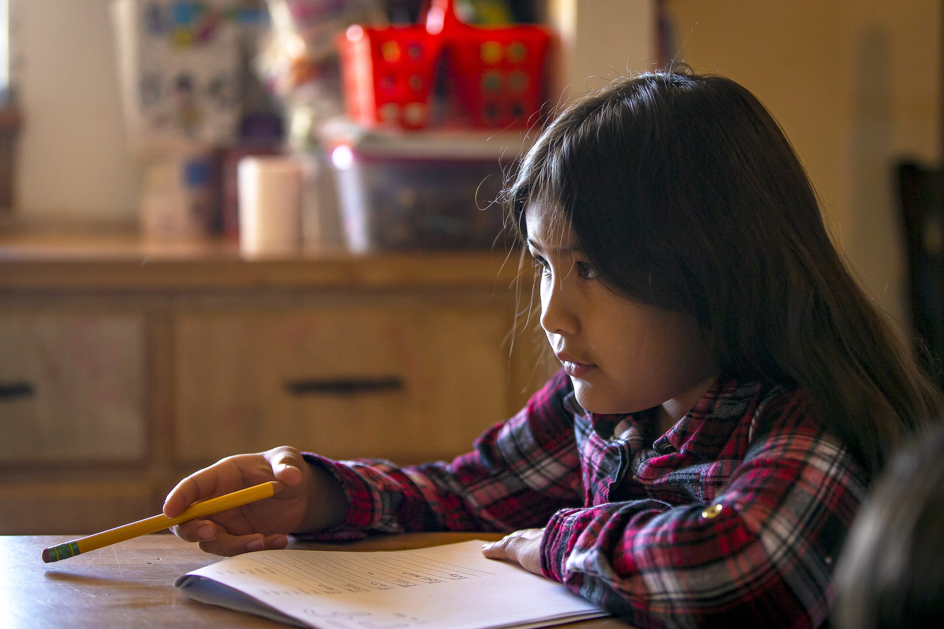 Fernanda Davila, 8, pauses to think as she completes homework in her Phoenix home on March 8, 2022.