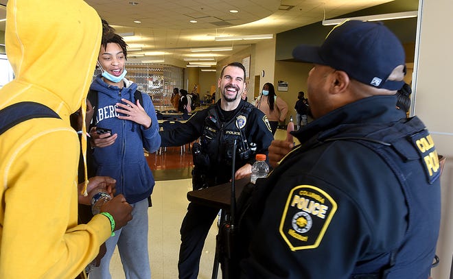 Battle High School sophomore Amosa Ndzegha, second from left, talks sports with Columbia police officers Chris Williams, center, and Cory Dawkins before school was dismissed early March 9. The officers were assisting at the school but not as school resource officers, which will soon return.