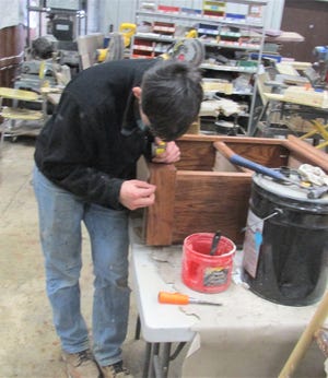 Ashland West Holmes Career Center senior Ben Lober puts some finish over nails on one of the 80 bookcases the students in John Staats' Construction Technology class made for area Head Start children who will receive them filled with books.