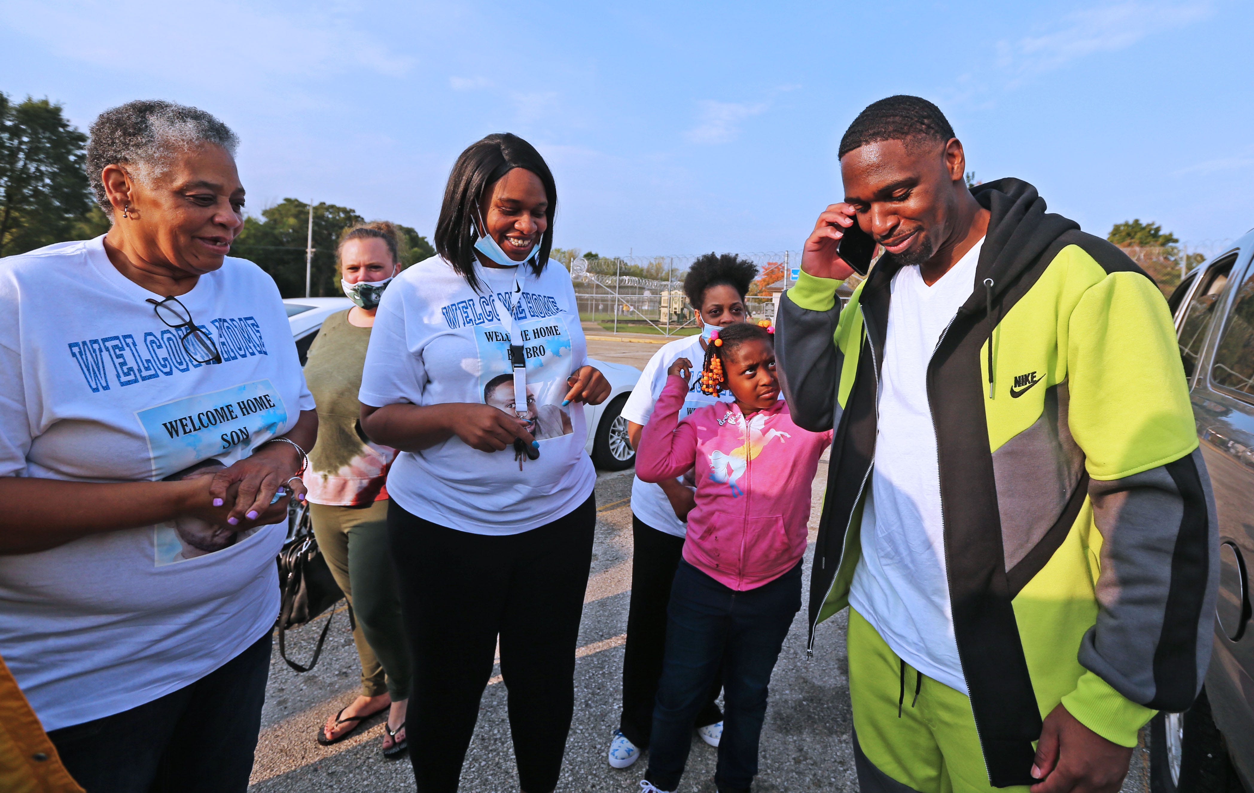 Surrounded by family members and friends including his mother, Doris Williams (from left), Nichole Anderson, sisters Tezra Williams, 36, and Leslie Williams, 42, and niece, Nia, 7,  Marlin Dixon, right, takes a call after being released from the John C. Burke Correctional Center.