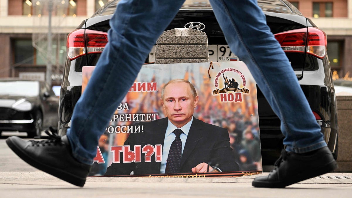 A placard featuring an image of Russian President Vladimir Putin and reading "We are with him for the sovereignty of Russia! And you?" is seen left in front of the Russian State Duma building in central Moscow.