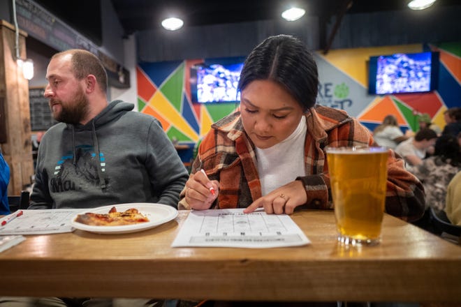 A music bingo player marks a song name on her sheet during a game at Switchyard Brewing Co. on North Walnut Street. Music bingo is played every other Wednesday evening with a DJ playing short bits of songs that game participants have to identify to put marks on their bingo grids.