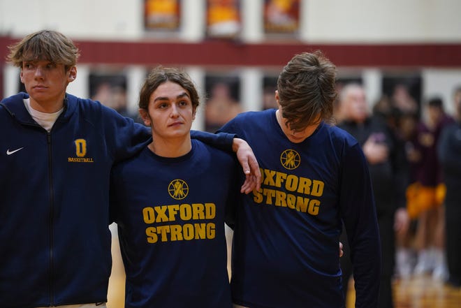 Oxford basketball player John Asciutto, center, stands with teammates during the national anthem before the Division 1 district semifinal game against Davison on Wednesday, March 9, 2022, at Davison High School.